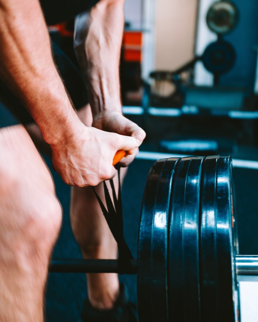 Hands gripping a loaded barbell with a resistance band attached